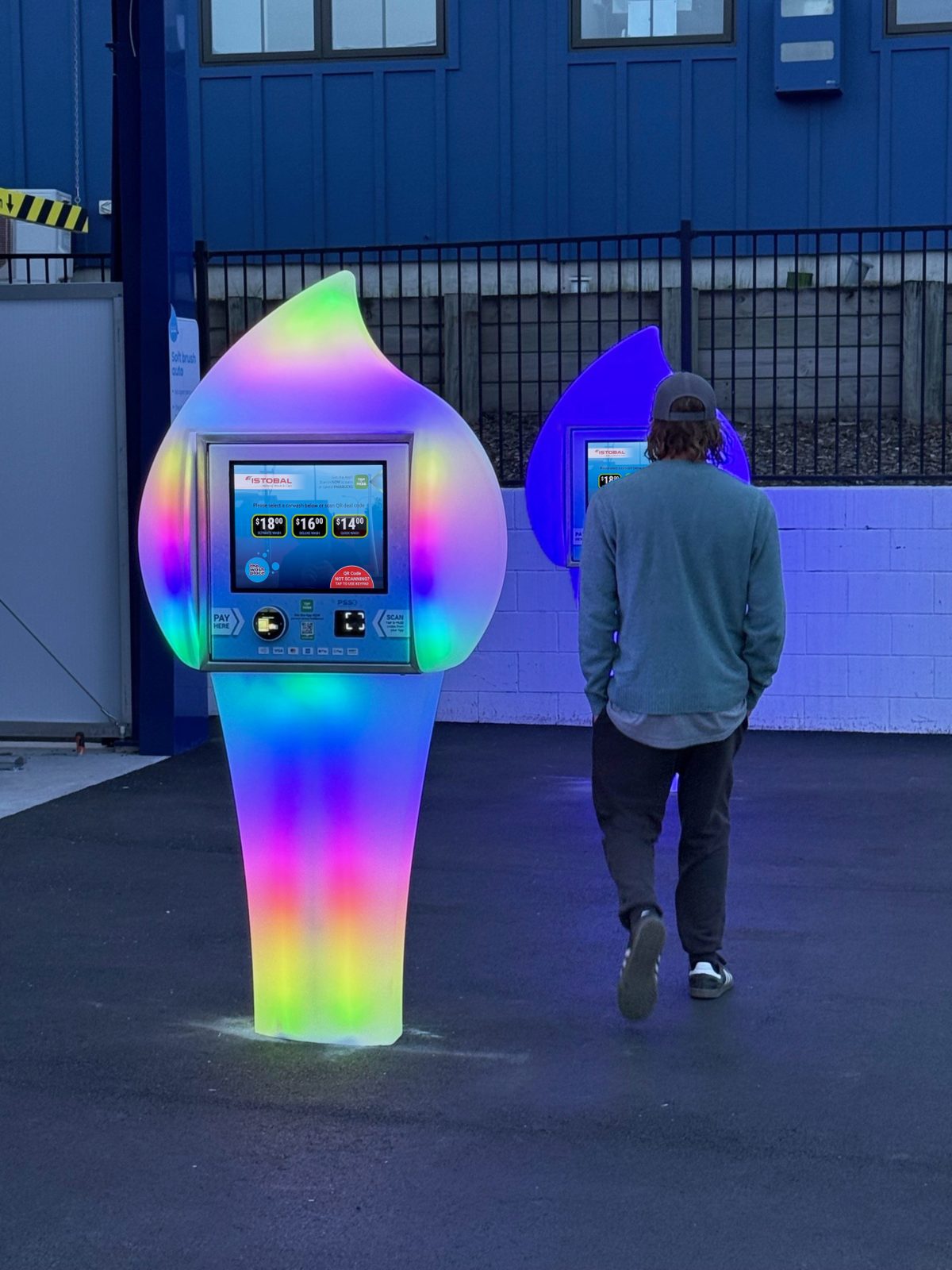 A customer at the rainbow-lit Paydrop plinth touchscreen