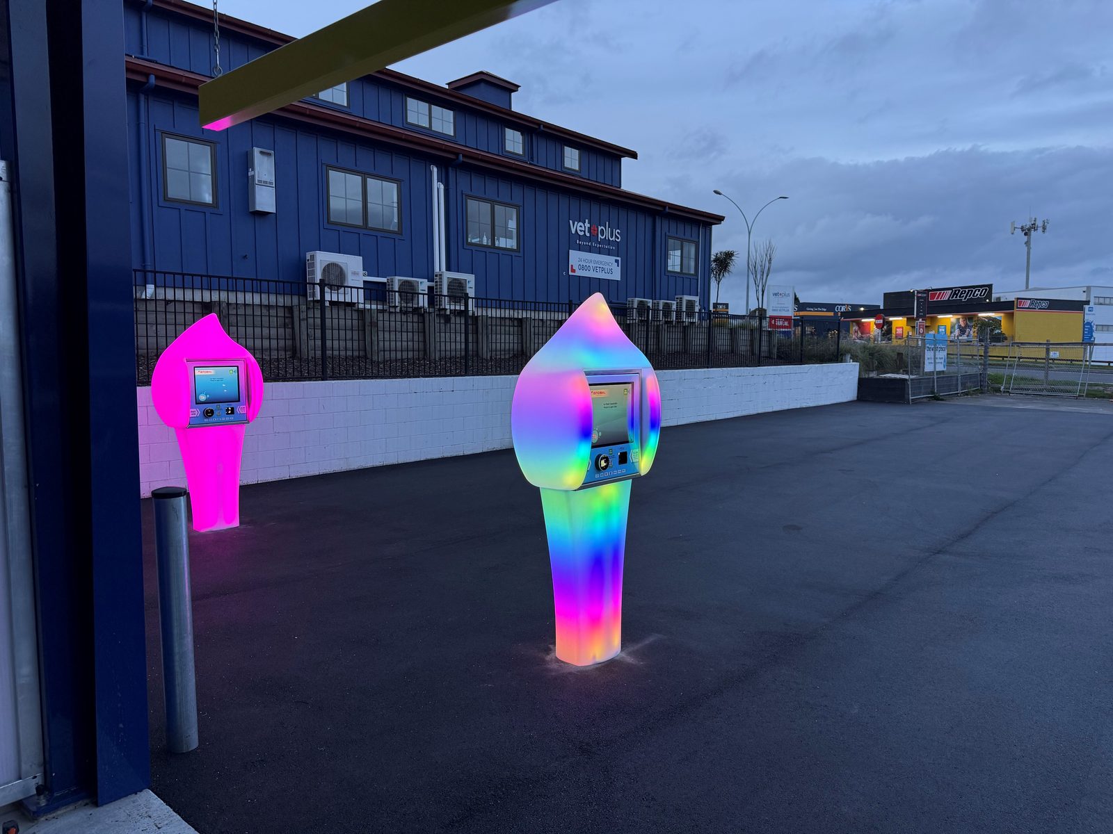 Pink and rainbow Paydrop plinths at dusk